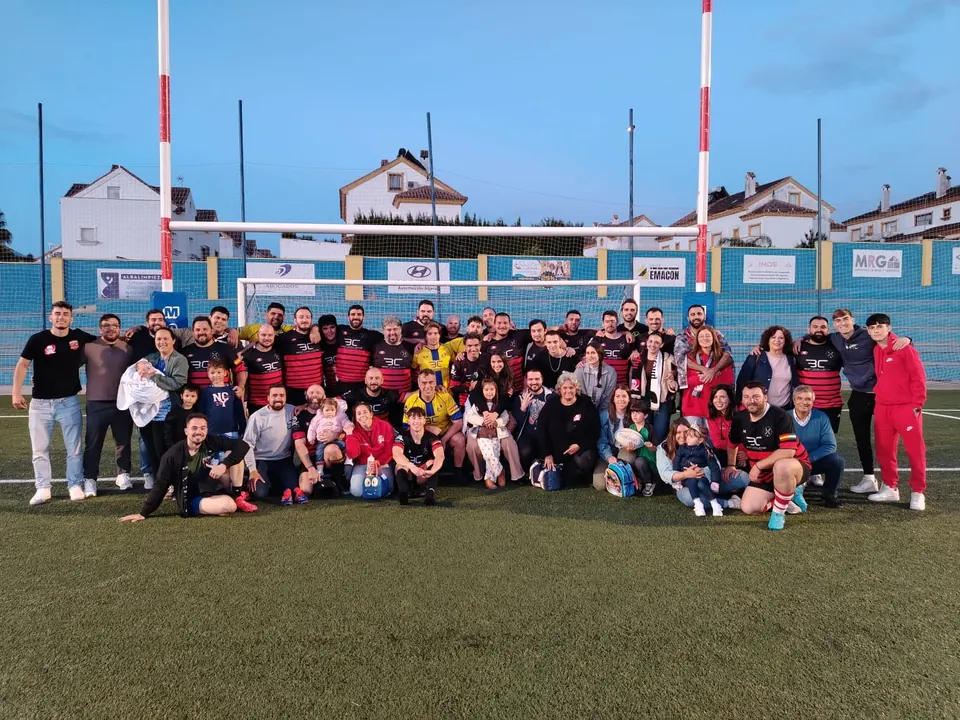Jugadores, entrenadores y familias del club posan juntos en el campo de rugby de Gines