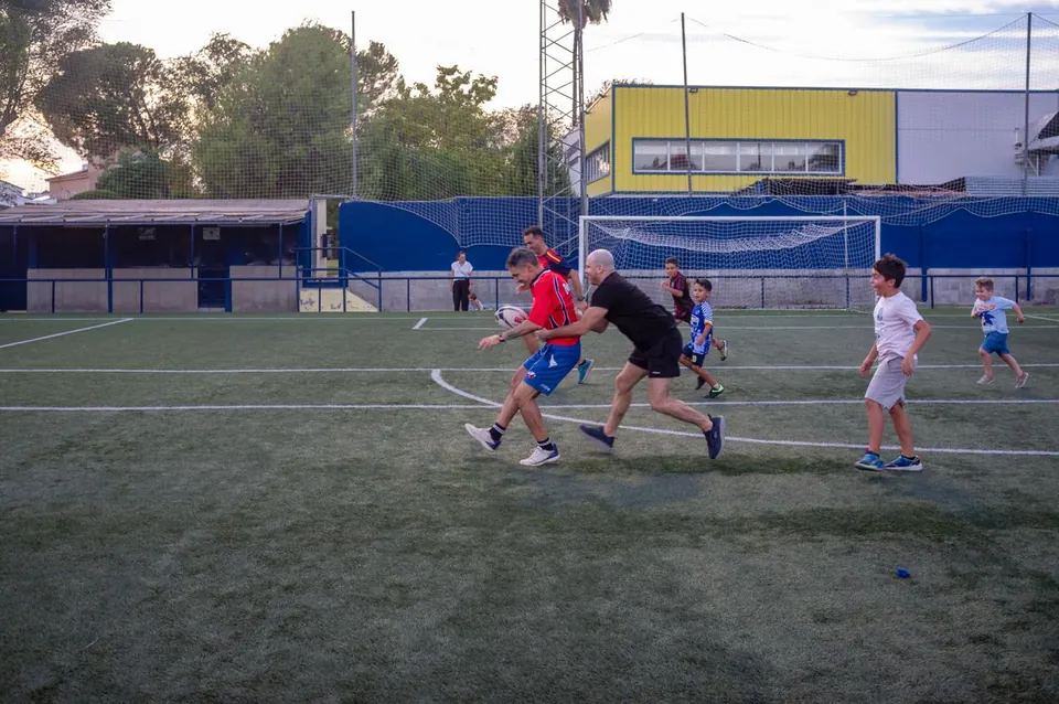 Niños de la escuela corren con el balón al atardecer en el campo de Gines