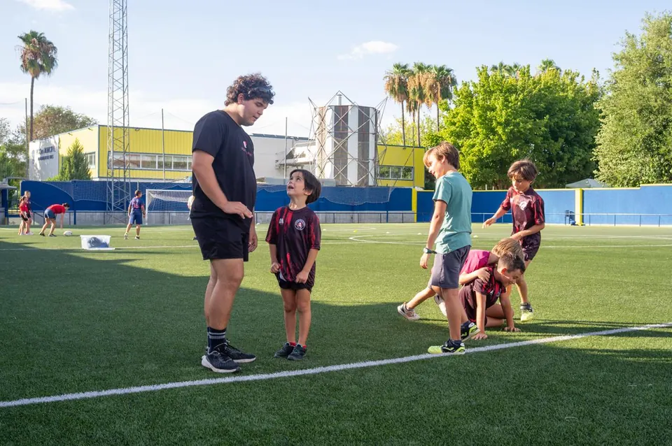Un entrenador del club guía a dos niños durante un ejercicio con balón